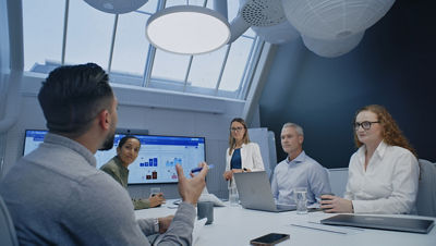 Colleagues sit around a desk in an office filled with natural light, engaged in a lively discussion.