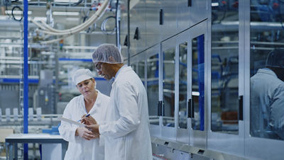  Two colleagues examine a clipboard with close attention in a factory environment.