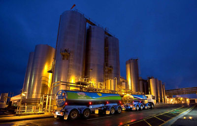 Fonterra truck in front of a lit factory at night