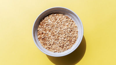 Bowl filled with rolled oats on a yellow background