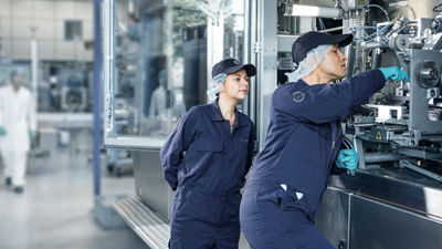 Dos trabajadores de fábrica reparando una máquina