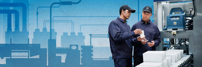 Especialistas olhando para embalagens cartonadas e máquina