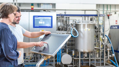 duas pessoas trabalhando na frente de uma tela sensível ao toque