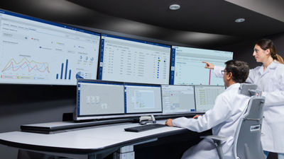 people in a control room looking at screens and pointing