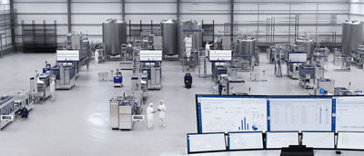 kvinna i fabrik tittar på flera skärmar