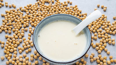 Bowl with soya beverage and soya beans on table