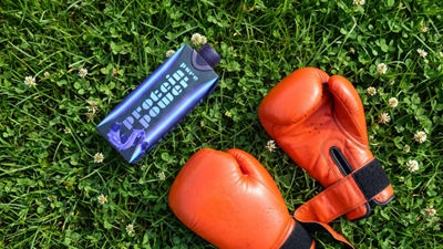 Boxing gloves and protein drink laying on the grass