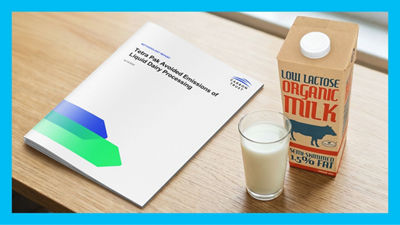 Brochure,  a glass of milk, and a Tetra Brik Aseptic package on a table