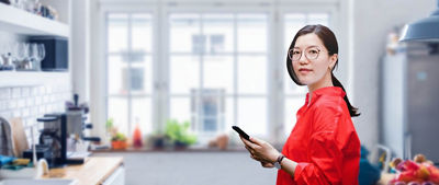 Mulher em pé na cozinha com celular