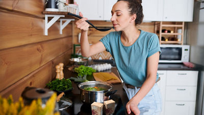 Woman cooking and tasting soup