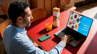 Man watching a juice webinar on a laptop while drinking juice