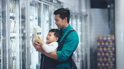 hombre con niño en la góndola de productos lácteos 