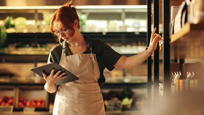 Woman in grocery store with tablet doing inventory