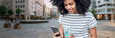 Young woman outside with phone and package