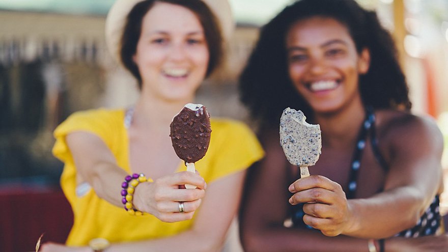 Two girls eating popsicles outside