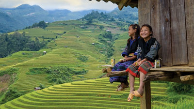 Girls sitting outside wooden house