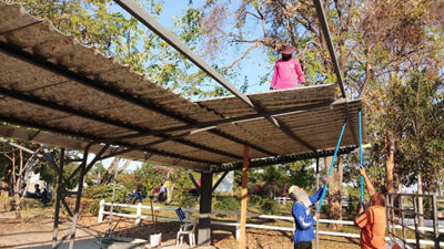 People building shelter with rooftiles made from recycled cartons