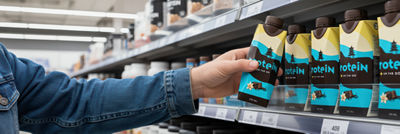 Hand grabbing food supplement and nutrition drink at shelf.