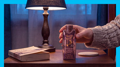 Lamp on bedside table, hand reaching for bedtime drink in carton package