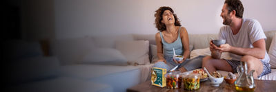 Happy people in sofa eating, salad and beans in Tetra Recart carton 