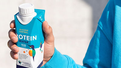 Hand holding protein water drink in Tetra Prisma Aseptic carton