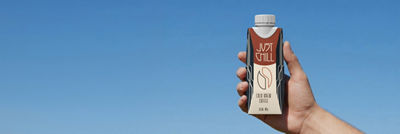 Hand holding Tetra Prisma Aseptic carton with ice coffee