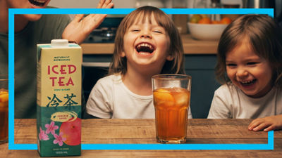 Laughing children with iced tea in glas and package beside.