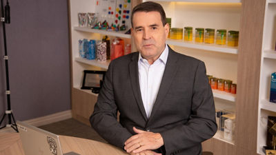 Luis Kuhl, diretor de Novos Negócios da Tetra Pak Brasil, posa sentado à mesa em escritório, com prateleiras ao fundo exibindo embalagens e produtos da empresa.