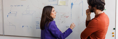 Two people in front of board in conference room