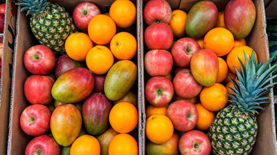 Apples, oranges, mangoes and pineapples arranged in boxes