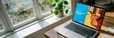 Laptop displaying a plant-based webinar on a table beside a window