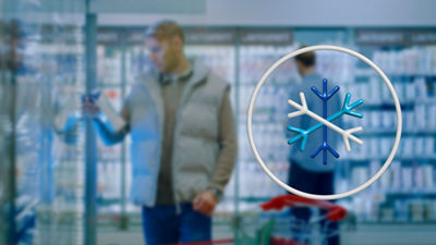 Man in the refrigerated section in the grocery store looking for milk