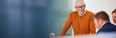 Man in orange shirt looking at a colleague