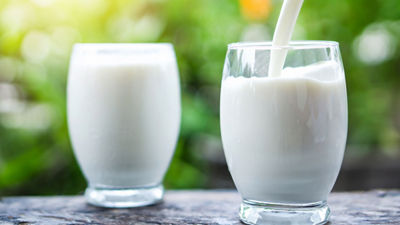 Milk being poured in a glass, green background