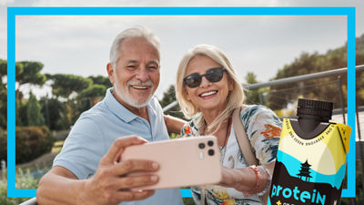 Coppia di anziani che si scatta un selfie, bevanda proteica in confezione di cartone Tetra Prisma Aseptic
