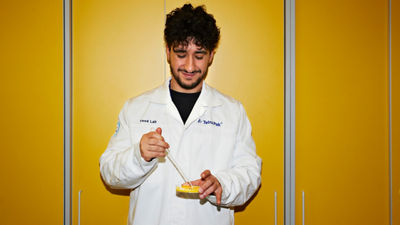 a man in white coat standing in front of a yellow wall