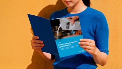 Person wearing a blue shirt holding a Tetra Pak case study brochure about Oatly's growth backed by automation.
