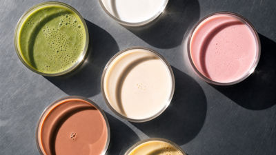 Petri dishes containing colourful plant-based samples on a stainless steel surface.