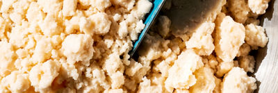 Close-up of crumbly okara soya pulp in a bowl with a scoop. 
