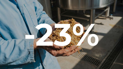 Worker holding spent grain, overlaid with −23%.