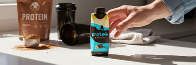 Hand reaching for protein drink in Tetra Prisma Aseptic carton