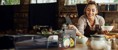 Woman preparing food in kitchen, ready meals in Tetra Recart cartons