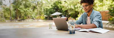 Young man with computer, protein milk in Tetra Prisma Aseptic carton package