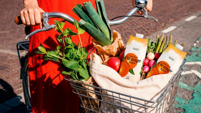 Cesta de bicicleta cheia de produtos frescos e embalagens cartonadas de suco