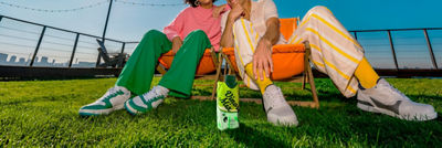 Man and woman sitting in beach chairs on the grass with an RTD alcoholic beverage in carton beside them