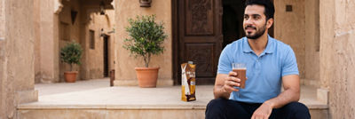Man sitting on stairs with protein drink in glass, Tetra Prisma Aseptic carton packaging