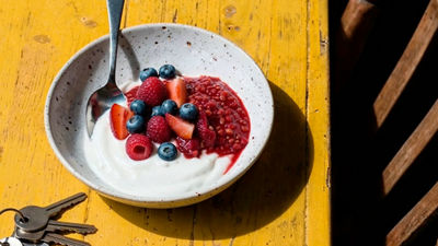 Bowl of yoghurt topped with berries and berry compote.