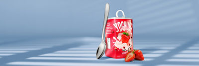 Tetra Reva package of strawberry yoghurt with a spoon and fresh strawberries.