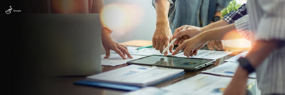 Tablet and printouts with graphs and data on table