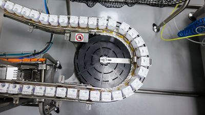 Carton packages moving along a curved conveyor in a production facility